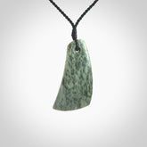 A hand carved curved contemporary drop pendant. This is a piece of genuine jade jewellery, hand carved by Raegan Bregmen. He has used rare New Zealand jade and has utilised his experience and carving skill to highlight the natural beauty of the stone. Delivered worldwide, postage is included in the price.